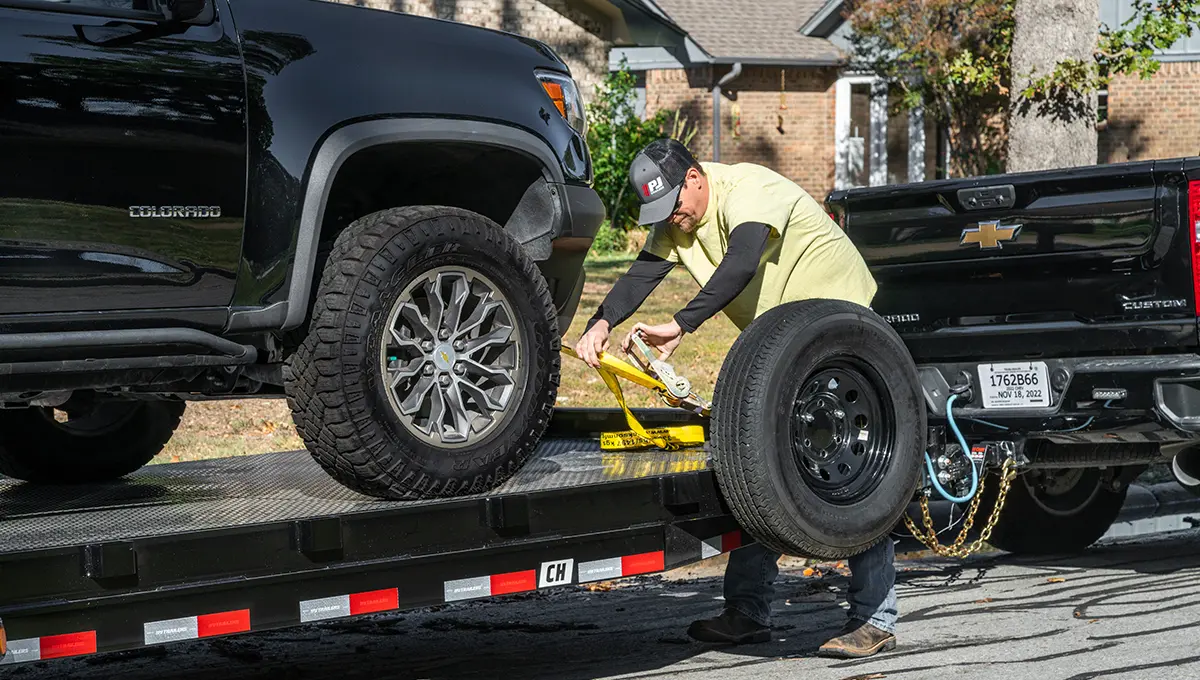 Man strapping a truck onto the Steel Deck Car Hauler