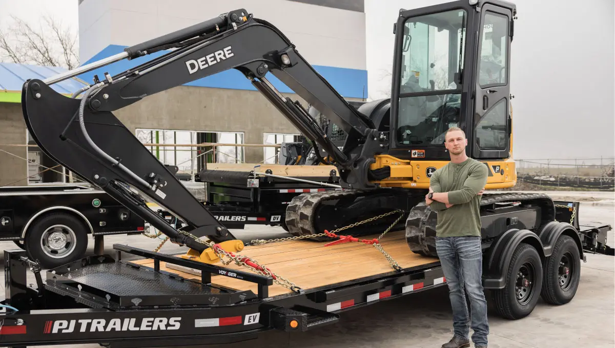 Worker standing next to a fully loaded Voyager Seamless I-Beam Equipment Trailer (EV)
