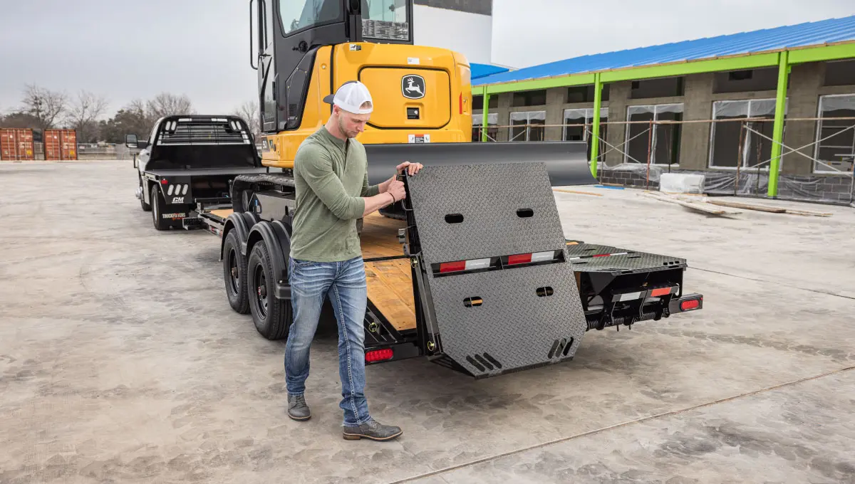 Worker lowering the knife-edge ramps of the Voyager Seamless I-Beam Equipment Trailer (EV)