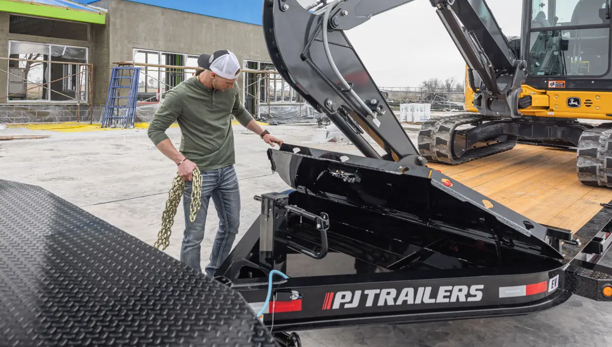 Worker loading chains into the toolbox of the Voyager Seamless I-Beam Equipment Trailer (EV)