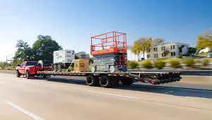 Truck driving with a fully loaded Low-Pro Flatdeck Trailer With Duals
