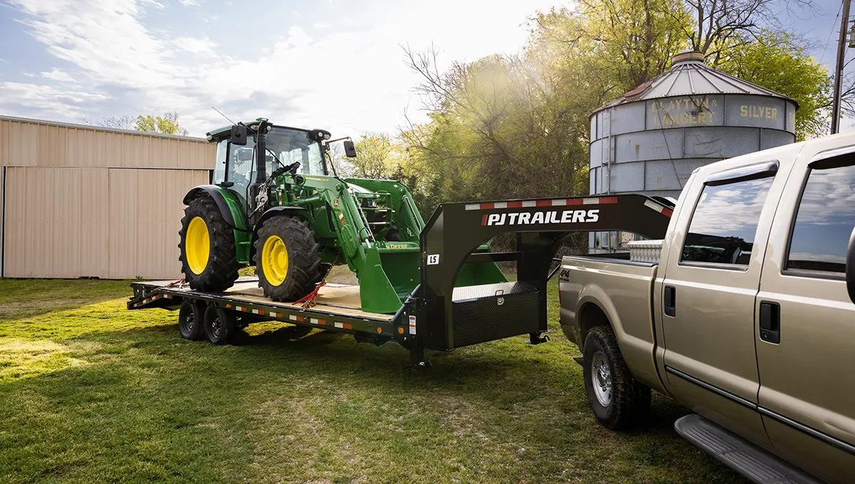 Low-Pro Flatdeck Trailer With 7K Singles hauling a John Deere front loader
