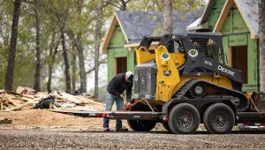 Worker securing a John Deere skid loader on the HD Equipment Tilt 6