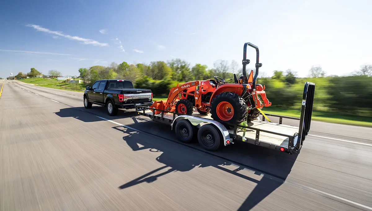 Truck carrying a Kubota front loader with the 83